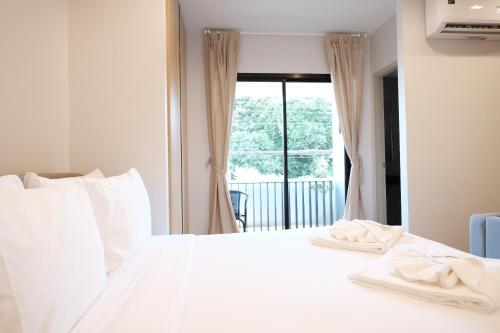a bedroom with a white bed with a window at Maleesa Place Hua Hin in Hua Hin