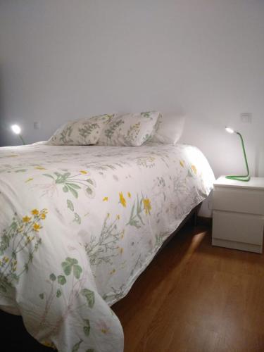 a bed with a white blanket with flowers on it at SUITE PLAYA Y MAR - sea view, wifi and AC in Melenara