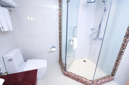 a bathroom with a glass shower with a toilet at Petals Inn in Bangkok