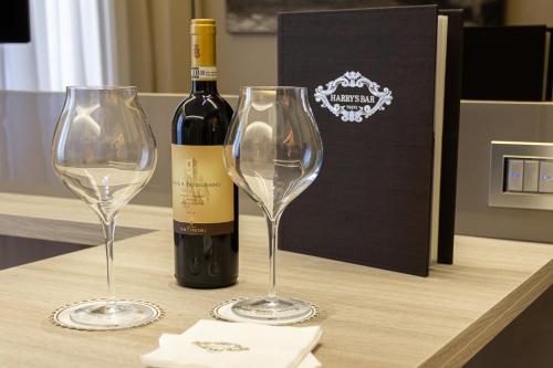 a bottle of wine and two wine glasses on a table at Harry's Bar Trevi Luxury Apartments - Spagna in Rome