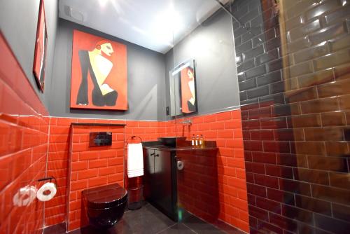 a red tiled bathroom with a toilet and a sink at The Lodge in Cospicua
