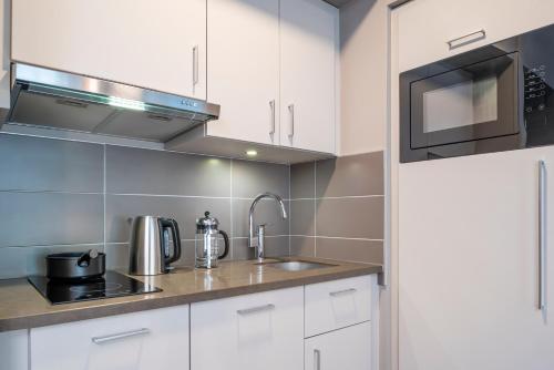 a kitchen with white cabinets and a sink and a microwave at Aparthotel Adagio Lille Centre Grand Place in Lille