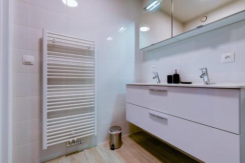 een witte badkamer met een wastafel en een douche bij Jef in Nieuwpoort