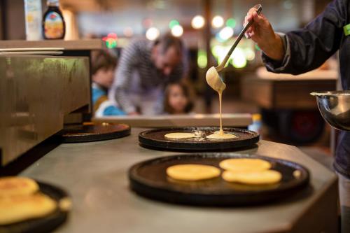 a man is cooking pancakes on a counter in a kitchen at Center Parcs De Eemhof in Zeewolde