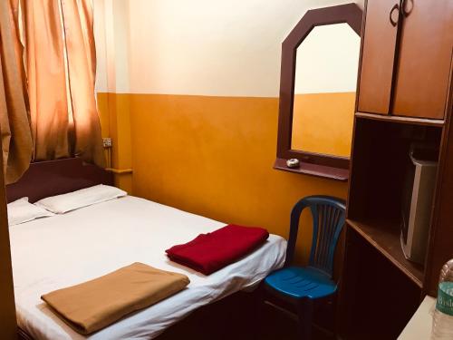 a small bedroom with a bed and a blue chair at Greens Residency in Bengaluru