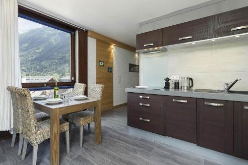une cuisine avec une table et des chaises ainsi qu'une fenêtre dans l'établissement APARTMENT BEAUSITE - Alpes Travel - Central Chamonix - Sleeps 2-4, à Chamonix-Mont-Blanc