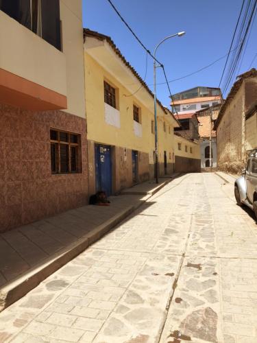 una strada vuota con un gatto seduto sul lato di un edificio di Asiriq Wasi Guest House a Cuzco