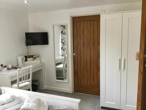 a room with a door and a desk with a mirror at The Sun B&B Rooms in Winforton