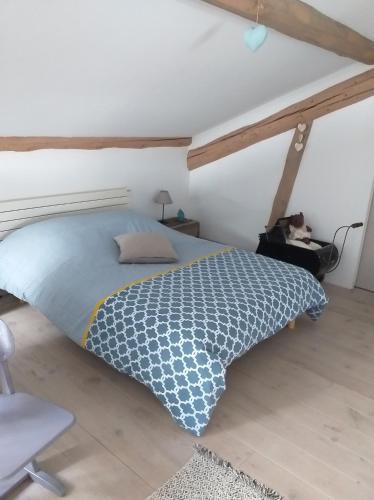 a bedroom with a bed with a cat sitting in a chair at Les 2 Granges Gîte in Bérig-Vintrange
