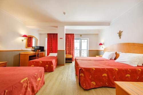 a hotel room with two beds with red sheets at Hotel Santo Amaro - SA Hotels in Fátima