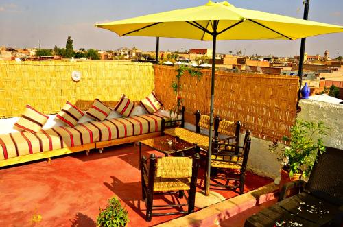 un patio con sofá, mesa y sombrilla en Riad Wink, en Marrakech