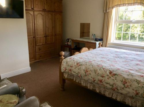 a bedroom with a bed and a desk and a window at Mill Farm B&B in Great Ayton