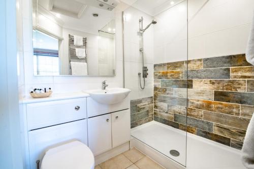 a white bathroom with a sink and a shower at The Lodge in Hunstanton