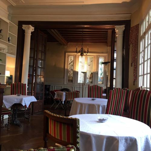 une salle à manger avec tables, chaises et fenêtres dans l'établissement La Villa L'Argentine, à Cabourg