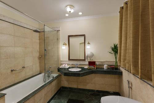a bathroom with a tub and a sink and a mirror at The Haveli Hari Ganga by Leisure Hotels in Haridwār