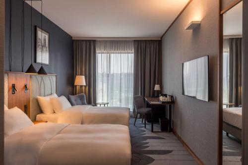 a hotel room with two beds and a desk at Radisson Hotel & Apartments Gdansk in Gdańsk
