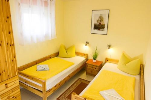 two beds in a room with yellow pillows at Ferienhof Schön in Zempin