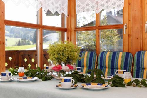a table with plates and cups and flowers on it at Ferienhof Degenhart in Mauth