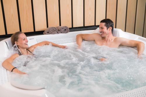 a man and woman sitting in a hot tub at 7Hotel&Spa in Illkirch-Graffenstaden