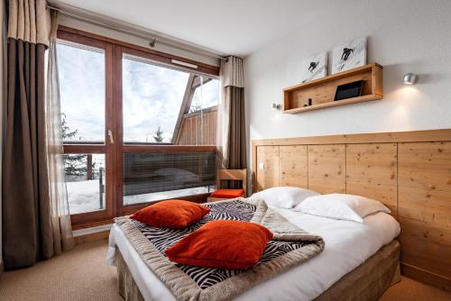 una camera con un letto con due cuscini sopra di travelski home premium - Résidence Le Roc Belle Face 4 stars ad Arc 1600