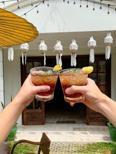 a person holding up two drinks in their hands at Elliebum Boutique Hotel in Chiang Mai