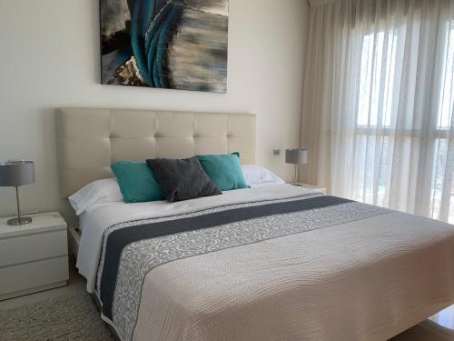 a bedroom with a large white bed with blue pillows at Vista Bella Apartment in Calpe
