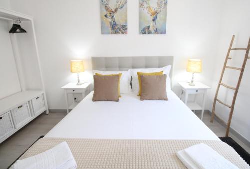 - une chambre avec un grand lit blanc et deux lampes dans l'établissement Apartamento Moderno nas Olaias a 5 minutos da Faculdade ISEL e IST, à Lisbonne