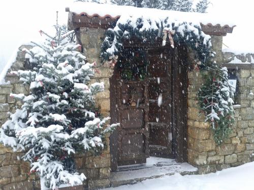 a snow covered christmas tree in front of a gate at Μαγεμένο Βουνό in Karpenision