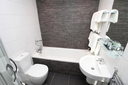 a bathroom with a tub and a toilet and a sink at Ascot House in Harrogate