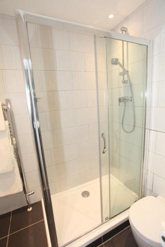 a bathroom with a glass shower with a toilet at Ascot House in Harrogate