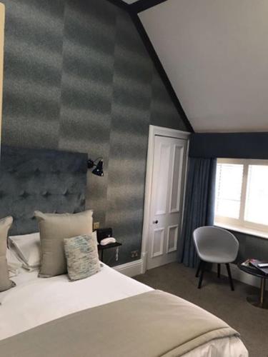 a bedroom with a bed and a chair and a window at Ascot House in Harrogate