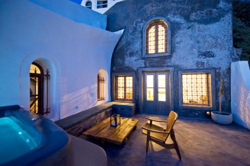 a room with a tub and a table and a chair at Sophia Luxury Suites in Imerovigli