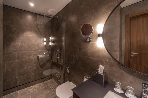 a bathroom with a shower and a sink and a mirror at Radisson Hotel & Apartments Gdansk in Gdańsk