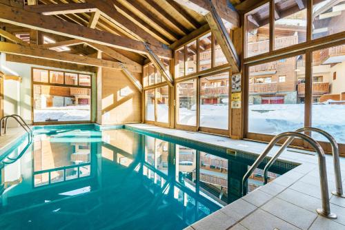 - une piscine dans un bâtiment avec fenêtres dans l'établissement travelski home premium - Résidence Les Chalets d'Edelweiss, à Plagne 1800
