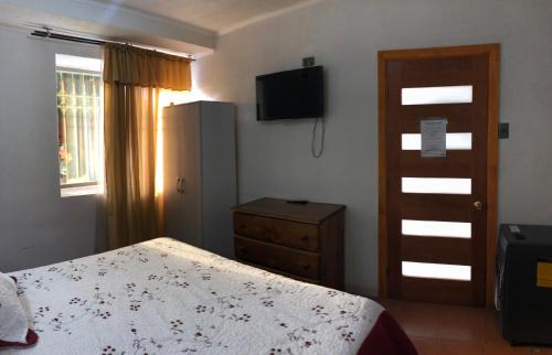 a bedroom with a bed and a dresser and a television at Residencial Victoria Said in Linares