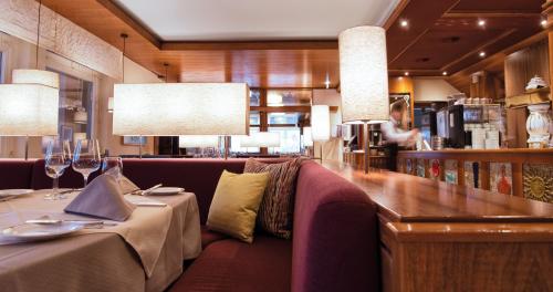 a restaurant with a couch and a table with wine glasses at Schlosshotel Dörflinger in Bludenz
