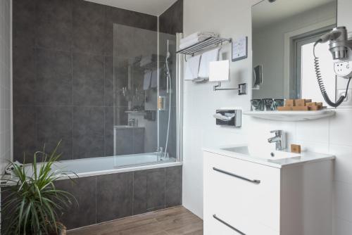 a bathroom with a tub and a sink and a shower at Hotel Le Richemont in Paris