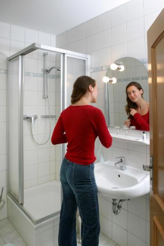 a woman standing in a bathroom looking at herself in the mirror at Hotel Boltenmühle in Gühlen Glienicke