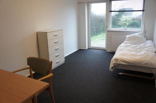 Schlafzimmer mit einem Bett, einem Tisch und einem Fenster in der Unterkunft id. 011. Jagtvej 50 a in Esbjerg