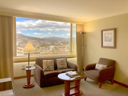 a living room with a couch and a large window at Swissotel Quito in Quito
