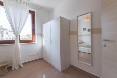 a bedroom with a white cabinet and a window at Appartamenti Orchidea e Glicine in Sommacampagna