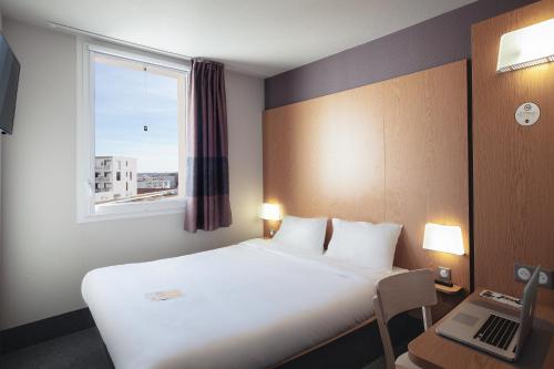 um quarto de hotel com uma cama e uma janela em B&B HOTEL Bordeaux Centre Bègles em Bègles