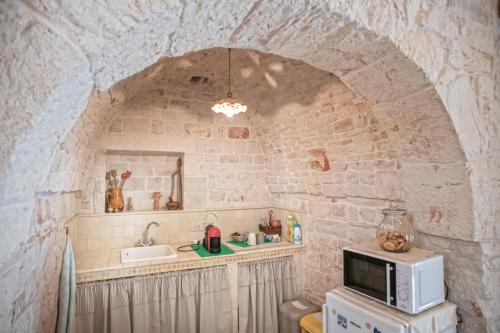 a small kitchen with a microwave and a sink at IL TRULLO GENTILE ALBEROBELLO in Alberobello