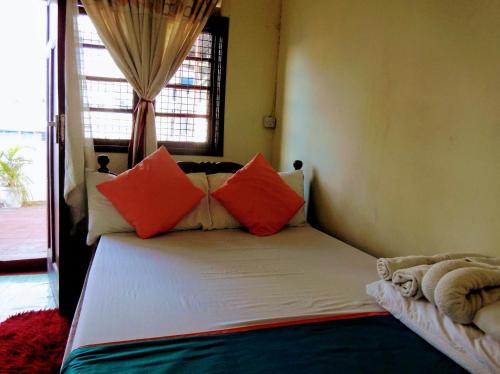 a bed with orange and orange pillows in a room at CDH Backpackers in Mombasa