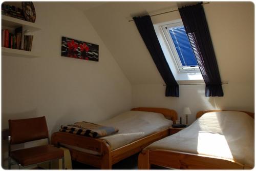 um quarto com 2 camas individuais e uma janela em Ferienhaus Naturblick am Tor zum Nationalpark Kellerwald em Frankenau