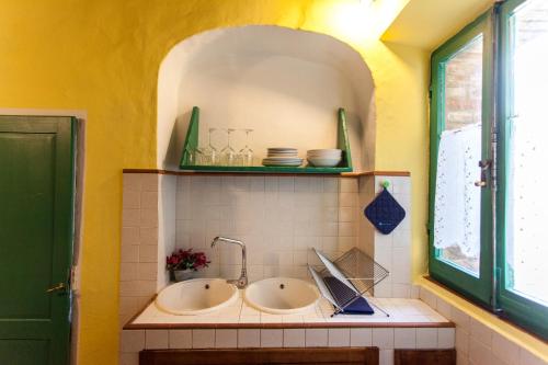 ein Badezimmer mit zwei Waschbecken und einer gelben Wand in der Unterkunft Foresteria del Teatro Povero in Monticchiello