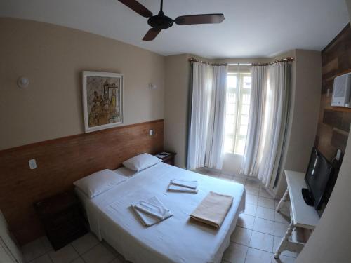 a bedroom with a white bed and a television at Pousada Portal do Mar in Cabo Frio
