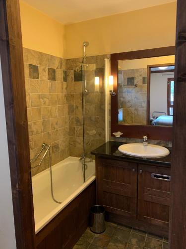 une salle de bain avec un lavabo, une baignoire et un miroir dans l'établissement Arc 1950 3 pièces 6 personnes Luxe Manoir Savoie, à Arc 1950
