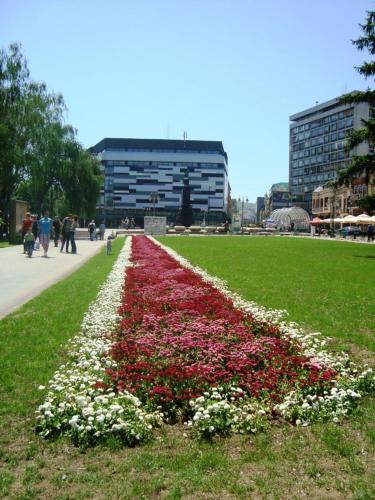 a garden with red and white flowers in a park at Glorious Rooms in Niš