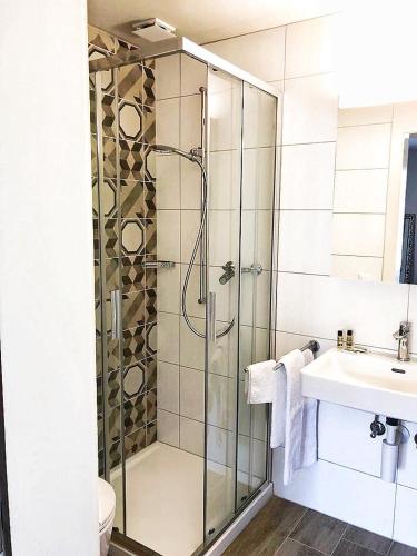 a bathroom with a glass shower and a sink at Hotel pas de Cheville in Conthey